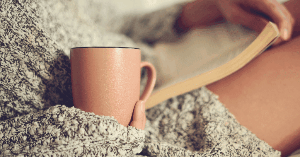Person relaxing with a cozy mug and book