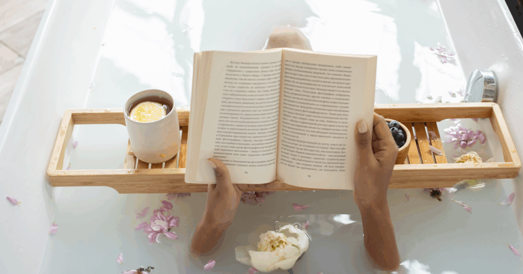 Peaceful woman relaxing in a warm bubble bath, holding a cup of tea and reading a book