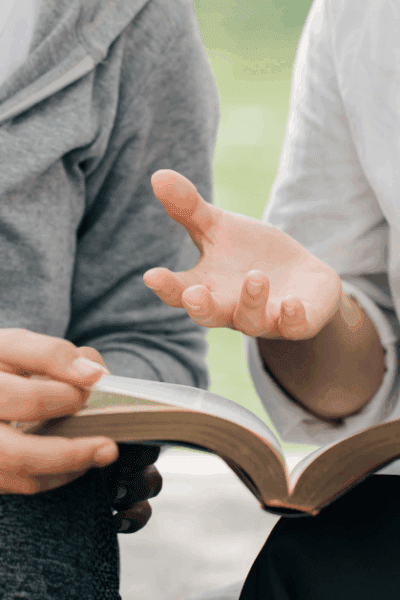 Casual conversation between two people, both holding the Bible.